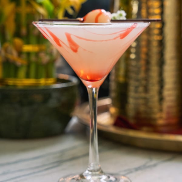 Pink martini with red swirls and a lychee garnish, on a marble table at Red Chilli.